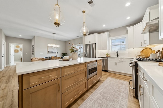 kitchen featuring hanging light fixtures, white cabinetry, extractor fan, and stainless steel appliances