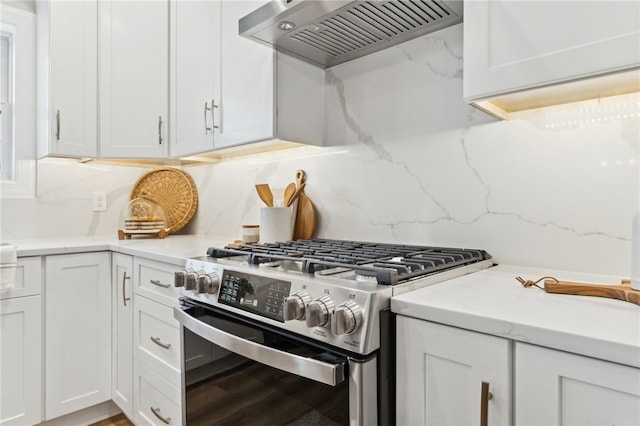 kitchen with white cabinets, custom range hood, stainless steel gas stove, and backsplash