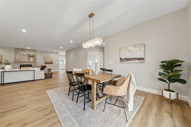 dining space with a stone fireplace and light wood-type flooring