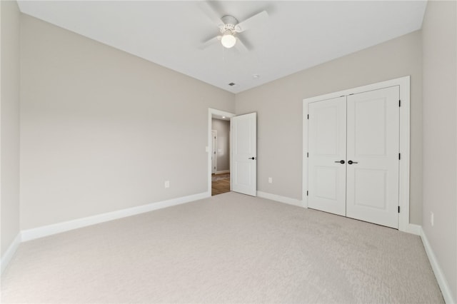 unfurnished bedroom with ceiling fan, a closet, and light carpet