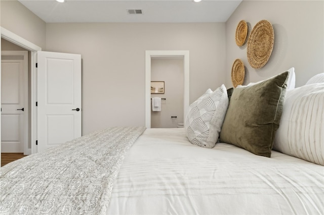 bedroom featuring hardwood / wood-style flooring and ensuite bathroom