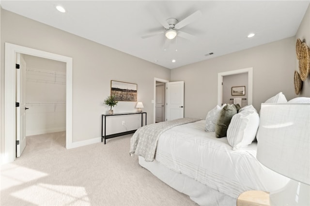 carpeted bedroom with ceiling fan, a walk in closet, and a closet