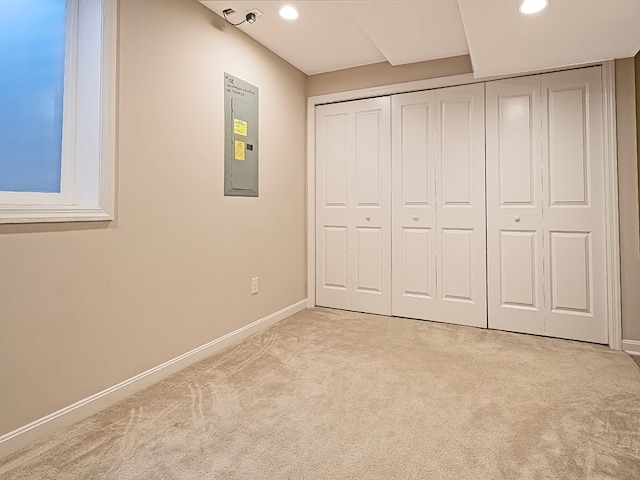 unfurnished bedroom with electric panel, light carpet, and a closet