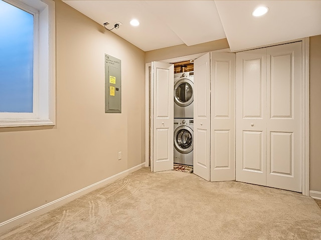 clothes washing area with electric panel, stacked washer and dryer, and light colored carpet