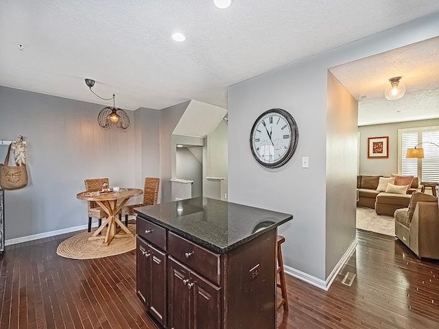 kitchen featuring a breakfast bar, dark brown cabinets, a kitchen island, and dark hardwood / wood-style floors