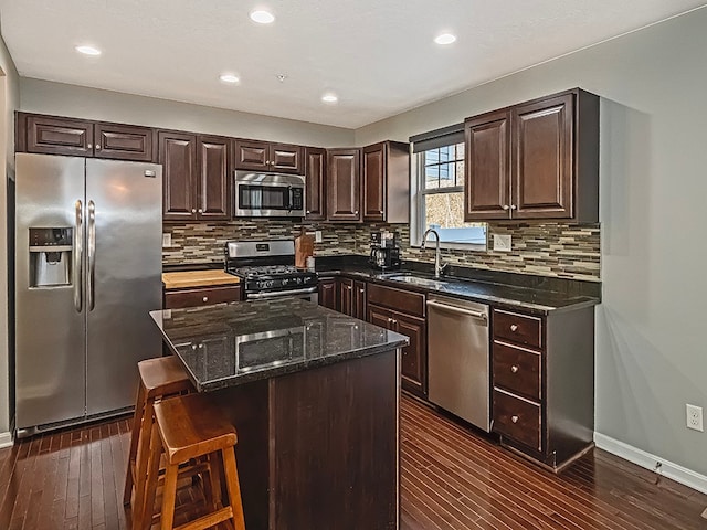 kitchen featuring stainless steel appliances, dark wood-type flooring, sink, a center island, and a breakfast bar area