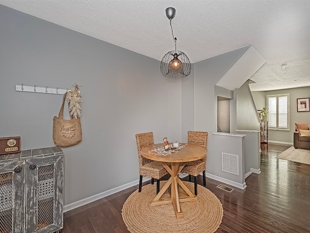 dining area with dark wood-type flooring and a textured ceiling