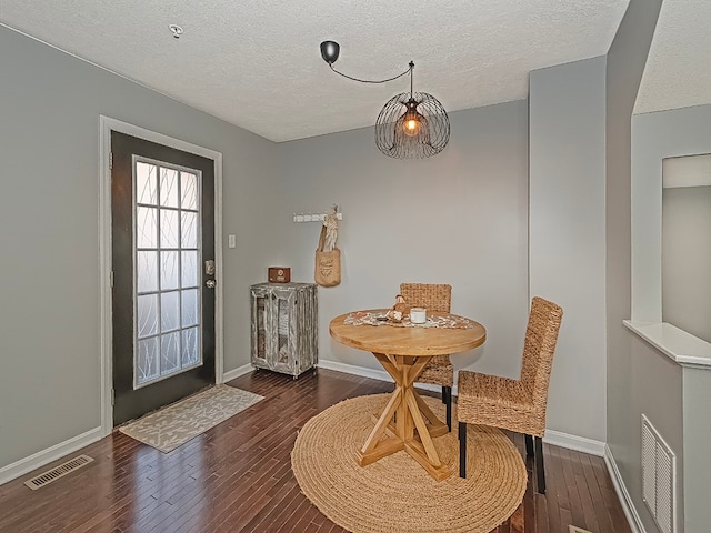 dining area with a textured ceiling and dark hardwood / wood-style floors