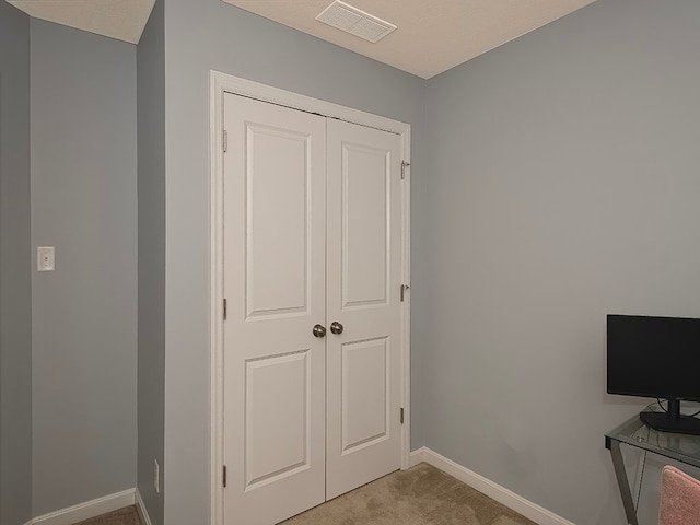 interior space featuring light colored carpet, a textured ceiling, and a closet