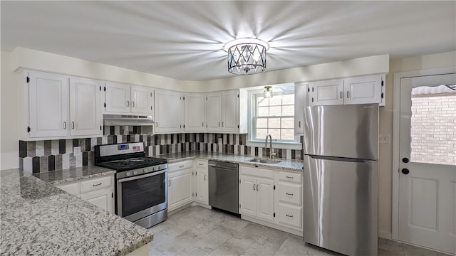 kitchen featuring sink, tasteful backsplash, light stone counters, white cabinets, and appliances with stainless steel finishes