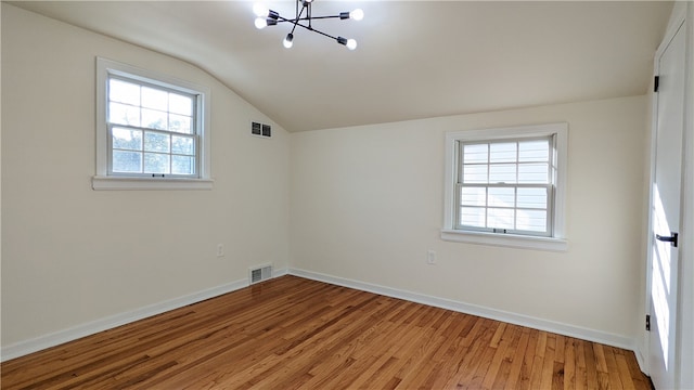 unfurnished room with a notable chandelier, light hardwood / wood-style floors, and vaulted ceiling