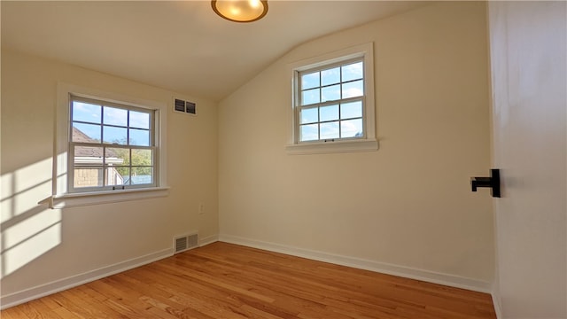 spare room featuring vaulted ceiling, light hardwood / wood-style flooring, and plenty of natural light