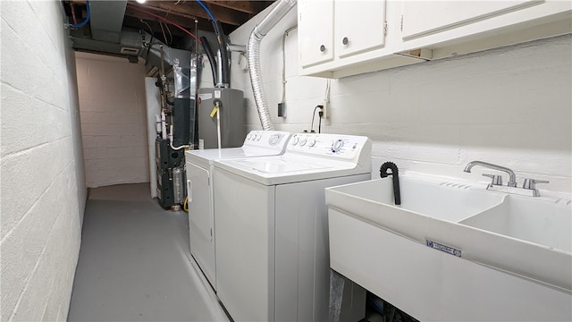 clothes washing area with cabinets, gas water heater, washer and clothes dryer, and sink