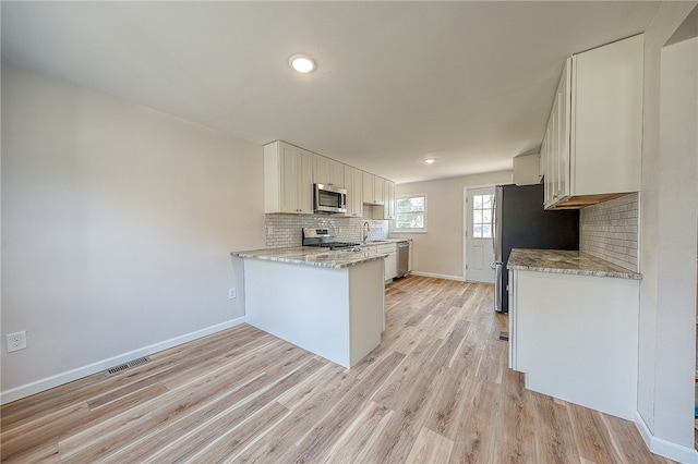 kitchen featuring white cabinets, light wood-type flooring, kitchen peninsula, and appliances with stainless steel finishes