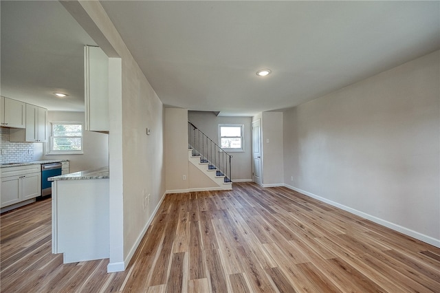 interior space featuring white cabinetry, light hardwood / wood-style flooring, a wealth of natural light, and tasteful backsplash