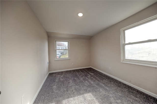 empty room featuring vaulted ceiling and dark colored carpet