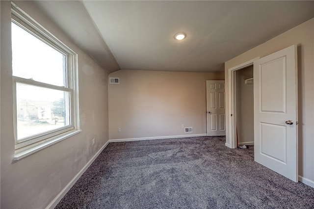 unfurnished bedroom with dark carpet and vaulted ceiling