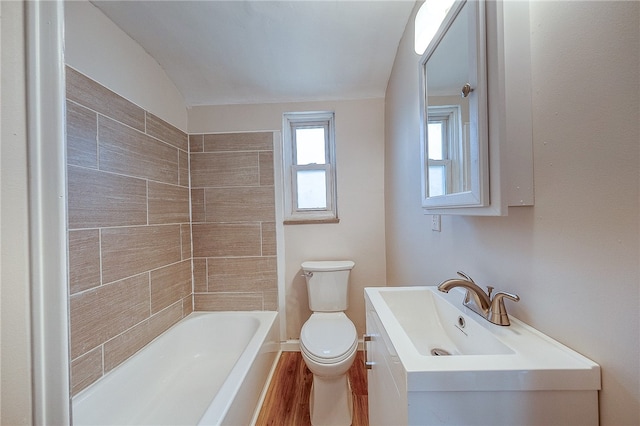 bathroom featuring a bathtub, vanity, vaulted ceiling, hardwood / wood-style flooring, and toilet