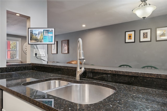 kitchen featuring white cabinets, sink, and dark stone counters