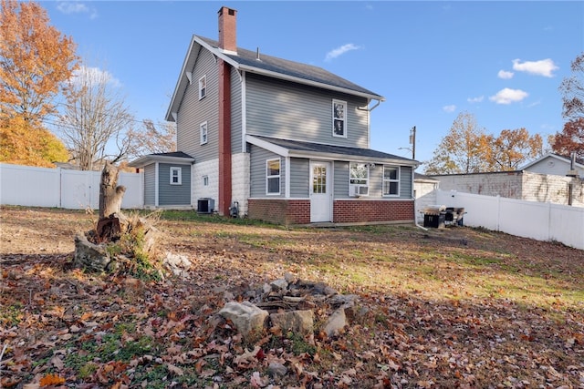 rear view of house featuring a fire pit and cooling unit