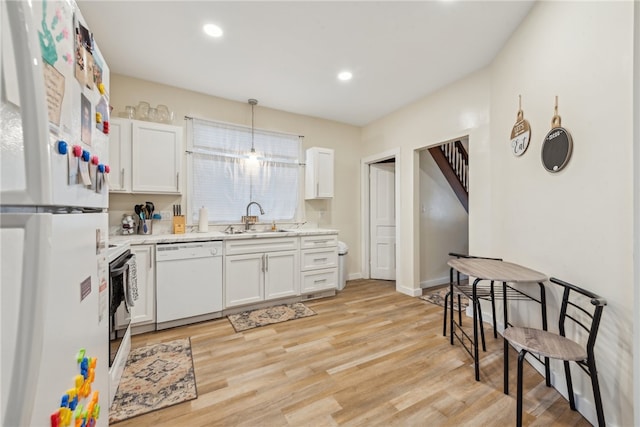 kitchen featuring sink, light hardwood / wood-style floors, decorative light fixtures, white appliances, and white cabinets