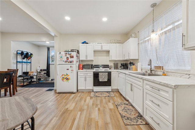 kitchen with white appliances, sink, white cabinets, light hardwood / wood-style floors, and hanging light fixtures