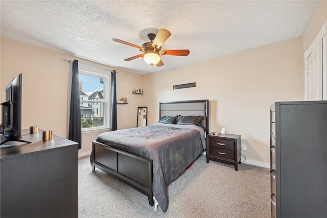 carpeted bedroom featuring ceiling fan and a textured ceiling