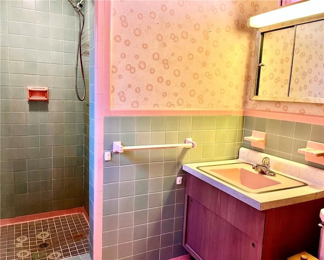 bathroom featuring a tile shower, vanity, and tile walls