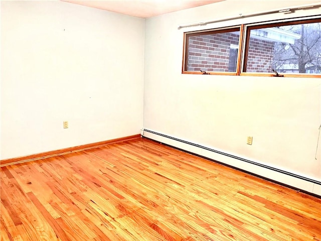 unfurnished room featuring light wood-type flooring and a baseboard heating unit