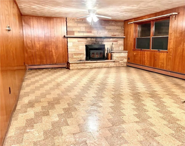 unfurnished living room with a fireplace, ceiling fan, baseboard heating, and wood walls