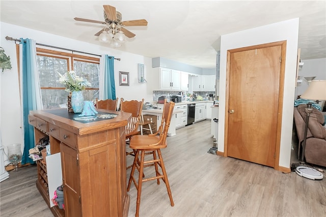 kitchen with ceiling fan, light hardwood / wood-style floors, a kitchen bar, decorative backsplash, and white cabinets