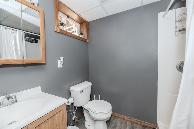 bathroom featuring a paneled ceiling, vanity, a shower with curtain, hardwood / wood-style flooring, and toilet