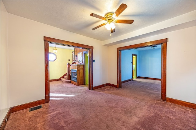 empty room with ceiling fan, carpet, and a textured ceiling