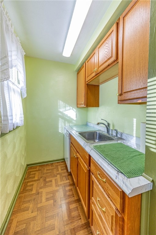 kitchen with white dishwasher, sink, and light parquet floors