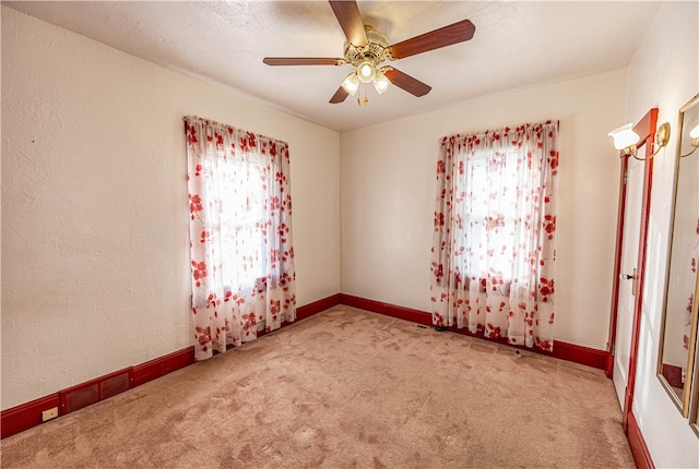 spare room featuring light carpet and ceiling fan