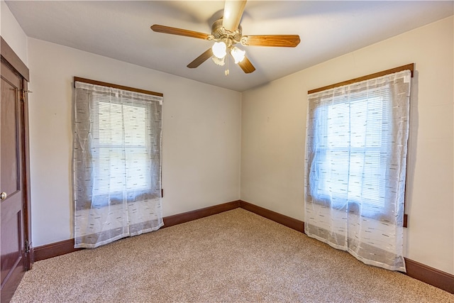 carpeted spare room featuring a wealth of natural light and ceiling fan