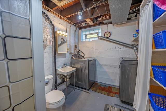 bathroom featuring washer and dryer, toilet, concrete flooring, and sink