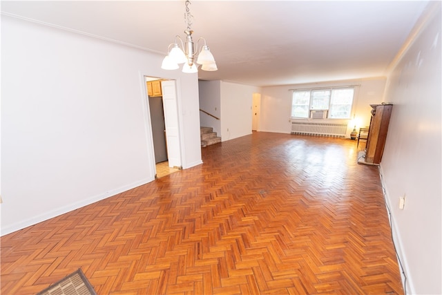 empty room with an inviting chandelier, radiator heating unit, and light parquet floors