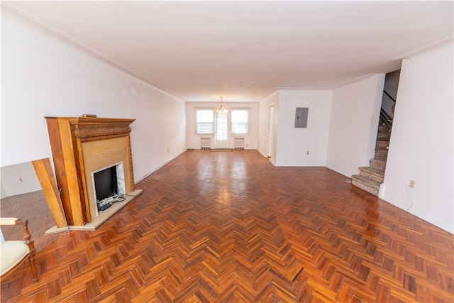 unfurnished living room featuring a chandelier, dark parquet floors, electric panel, and ornamental molding