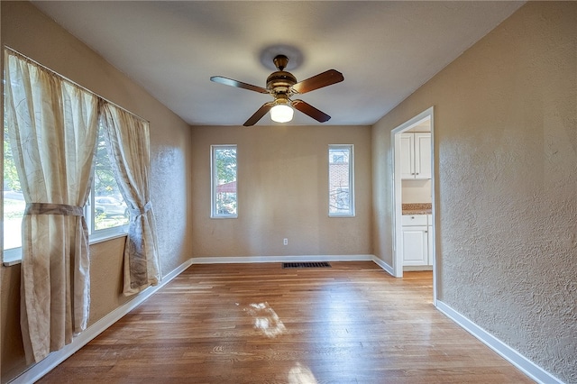 empty room with ceiling fan and light wood-type flooring