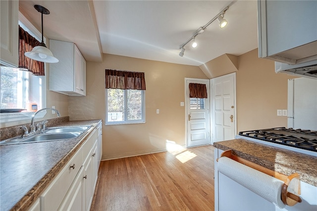 kitchen featuring white cabinetry, light hardwood / wood-style flooring, hanging light fixtures, and sink