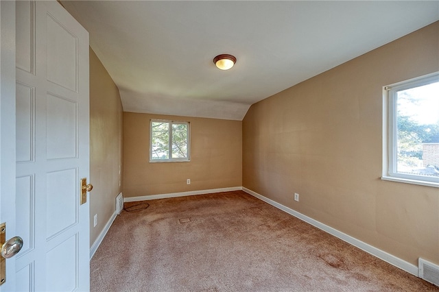 empty room featuring light colored carpet and lofted ceiling