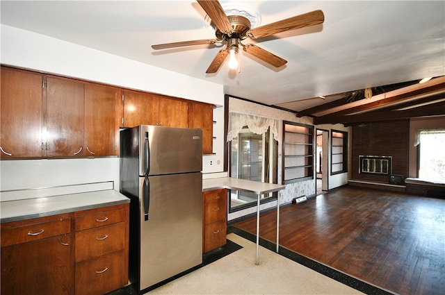 kitchen featuring stainless steel fridge, dark hardwood / wood-style flooring, ceiling fan, beamed ceiling, and a fireplace