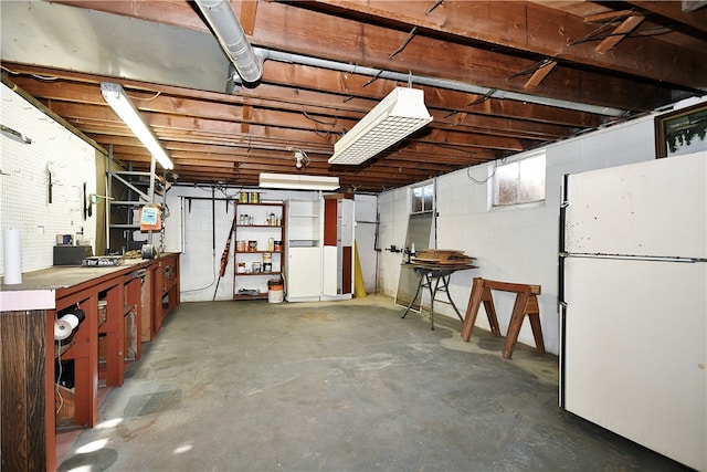 basement with a workshop area and white refrigerator