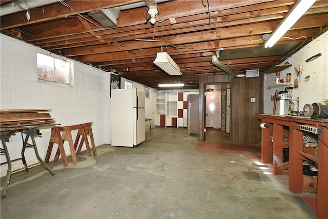 basement featuring a workshop area and white fridge