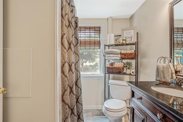 bathroom with tile patterned flooring, vanity, toilet, and walk in shower