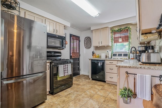 kitchen with black appliances, light stone counters, sink, and cream cabinetry