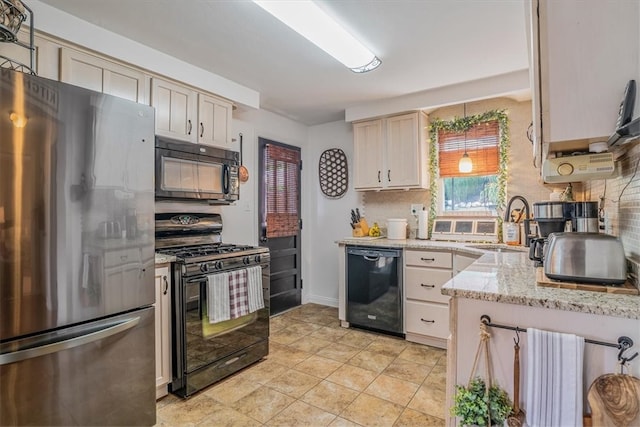 kitchen featuring tasteful backsplash, light stone counters, sink, black appliances, and cream cabinets