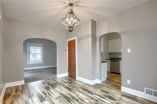 unfurnished room with a chandelier and light hardwood / wood-style floors