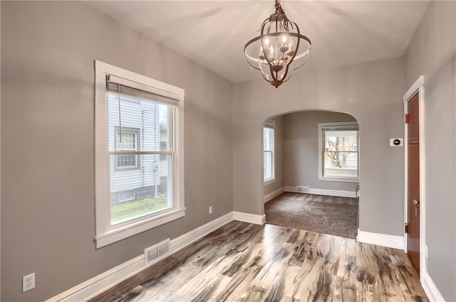 spare room featuring hardwood / wood-style flooring, a healthy amount of sunlight, and a chandelier